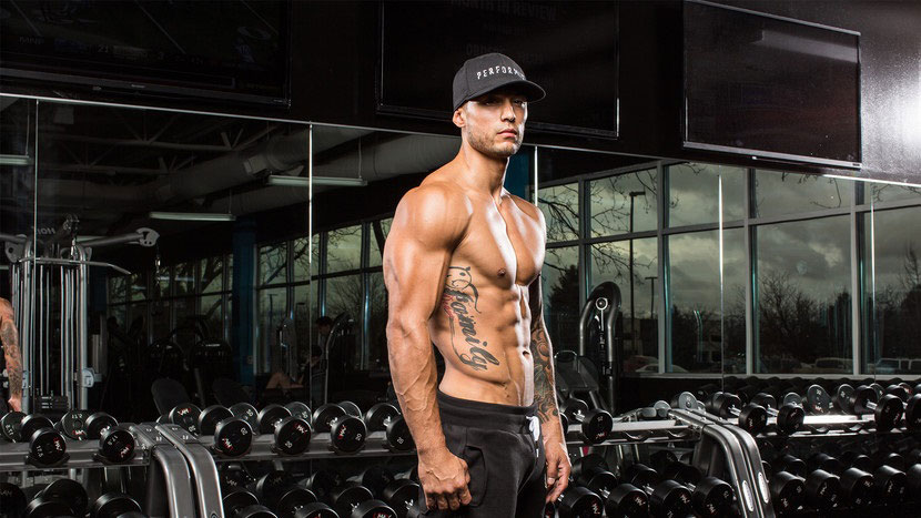 Michael Vazquez showing off his abs posing in the gym.