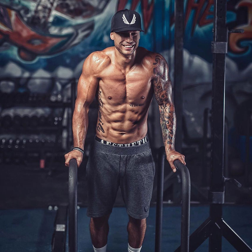 Michael Vazquez smiling whilst holding a pose on parallel bars.