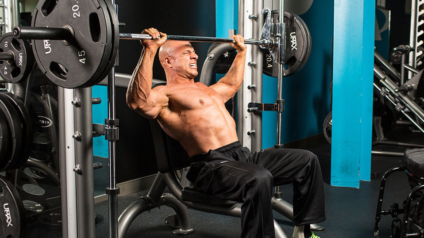 Nick Scott performing an incline chest press on a Smith machine.