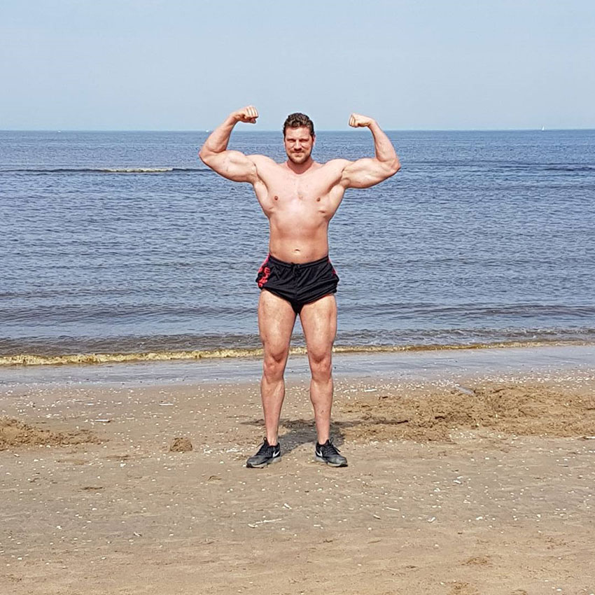 Olivier Richters flexing his biceps on the beach.