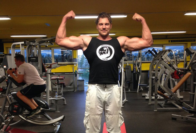 Olivier Richters flexing his biceps in the gym.