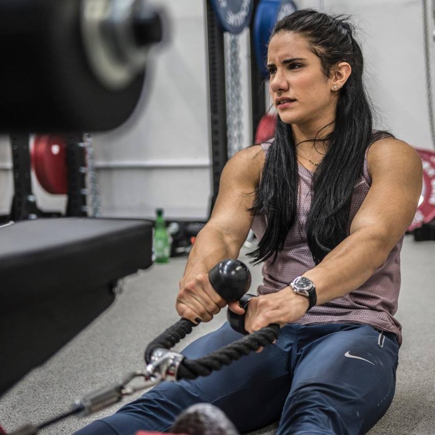 Stefanie Cohen doing cable rows with a tired expression on her face