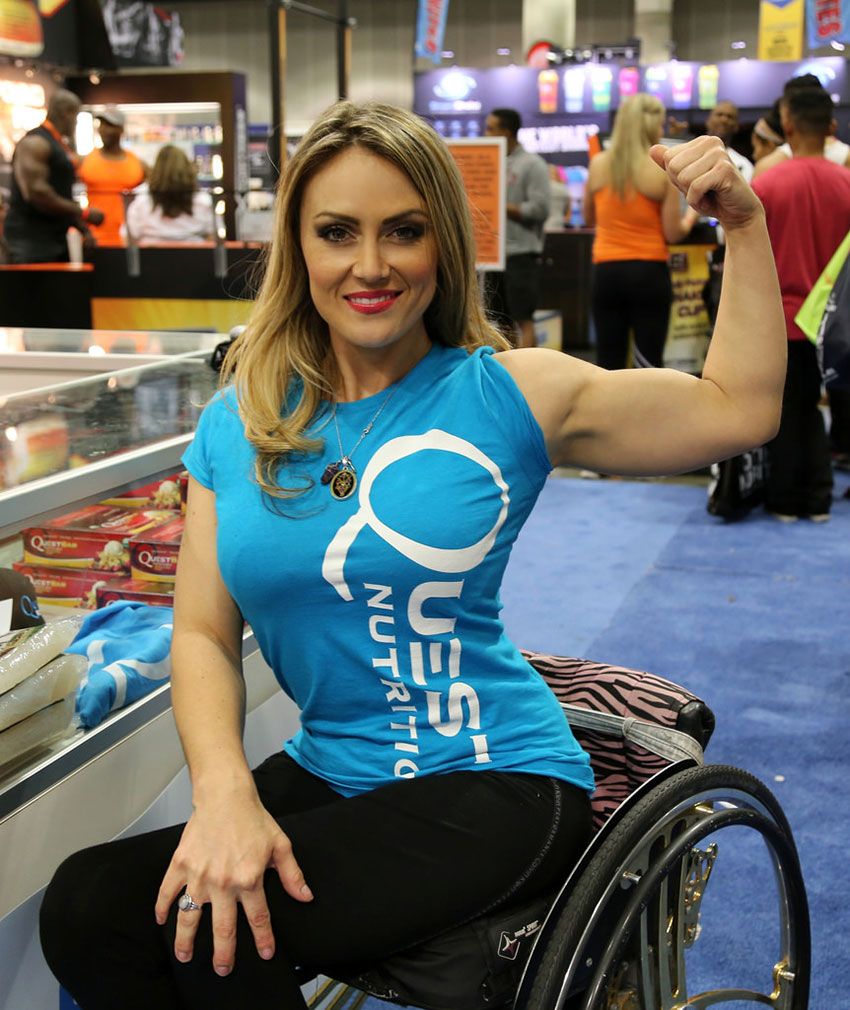 Tiphany Adams flexing her bicep at a fitness event.