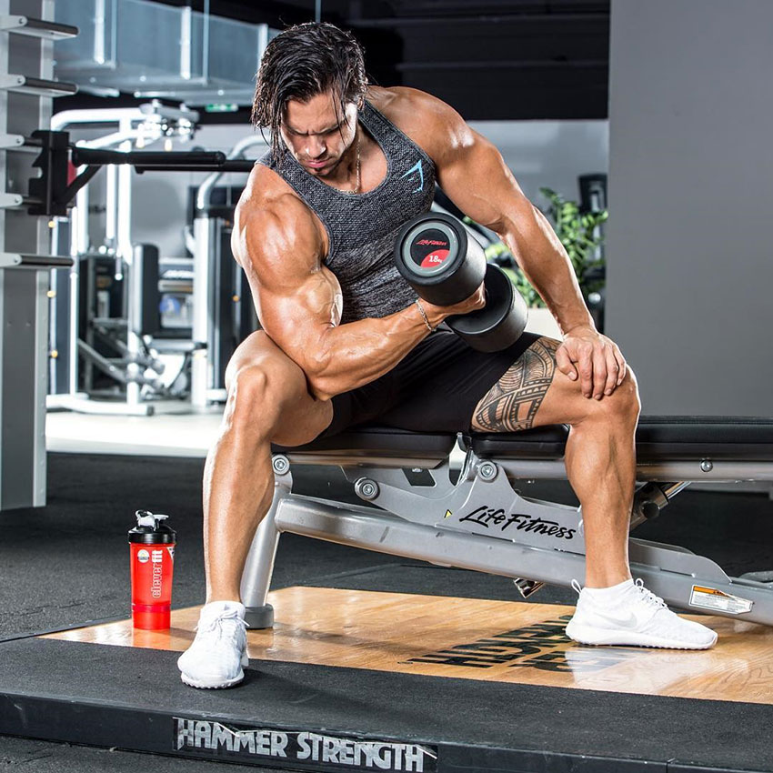 Alon Gabbay performing bicep curls in the gym.