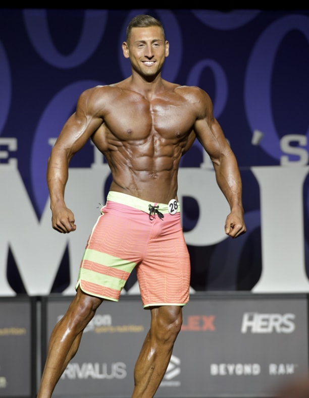 Anthony Scalza posing on the Men's Physique stage, looking conditioned and muscular