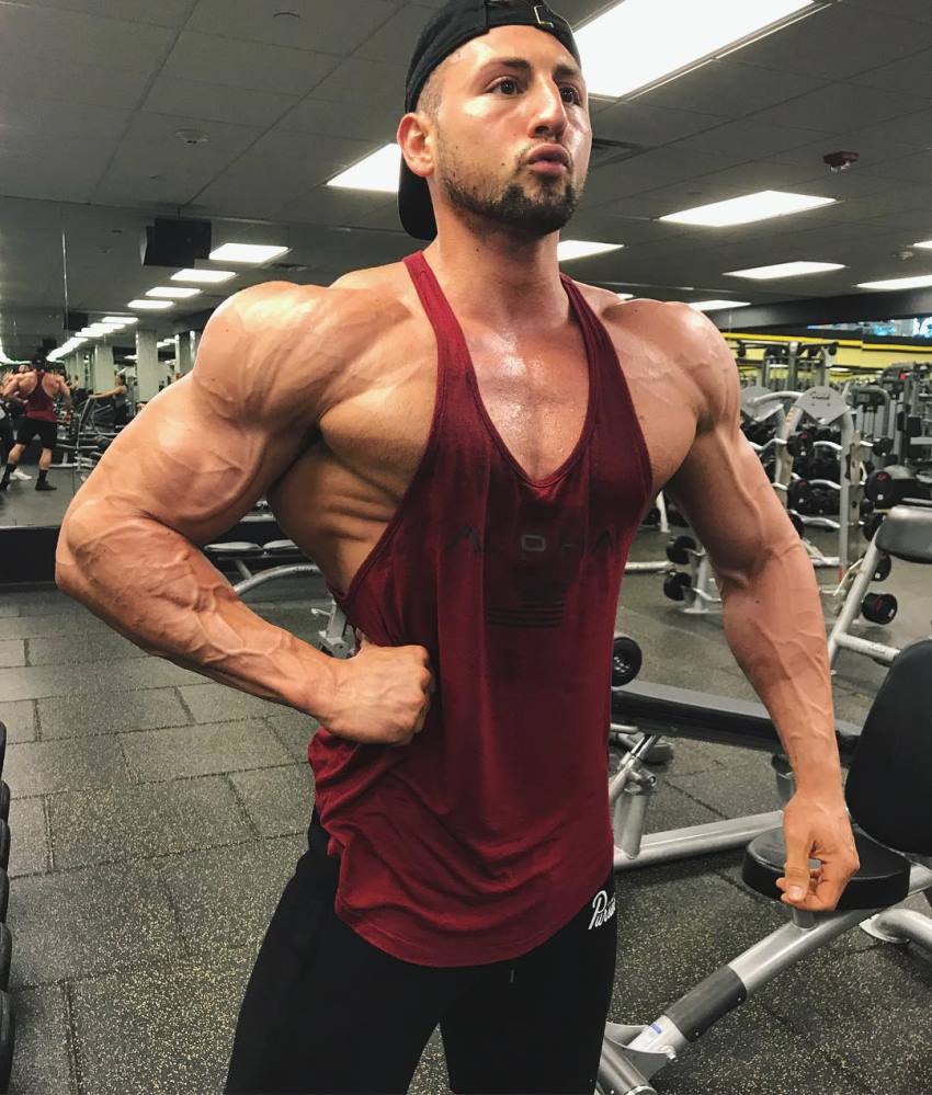 Anthony Scalza posing in the gym in a red tank top