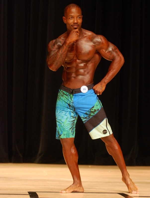 Antoine Williams posing on the Men's Physique stage, looking aesthetic and ripped