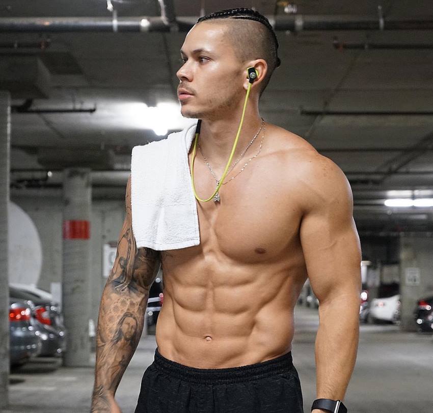 Brandon Schram standing shirtless in a parking garage, looking fit and muscular