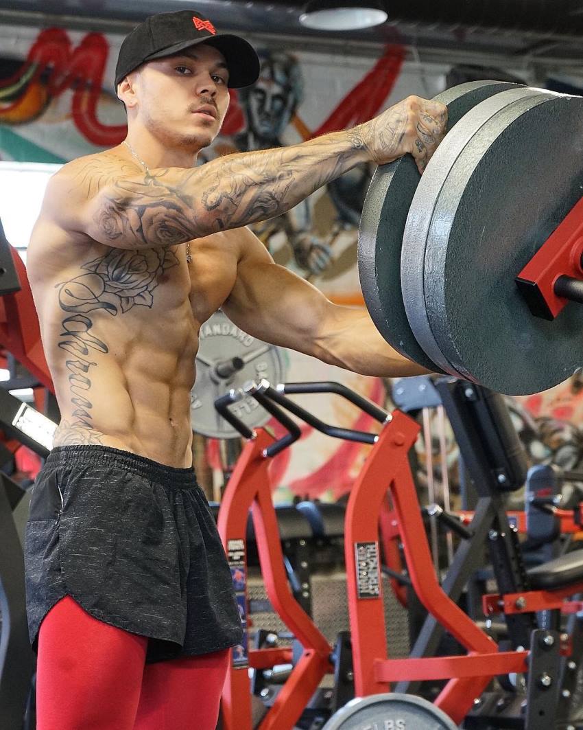 Brandon Schram putting weight plates on a machine looking fit and ripped