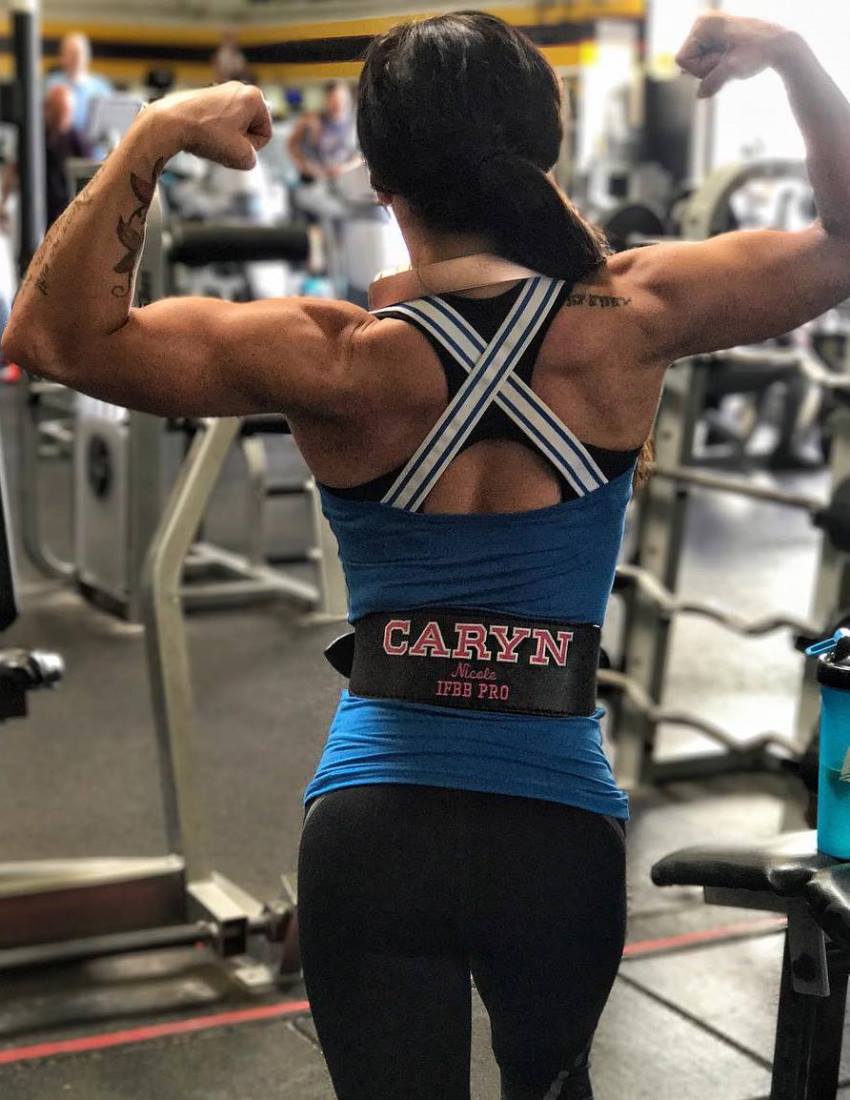 Caryn Nicole Paolini doing a back double biceps pose in the gym