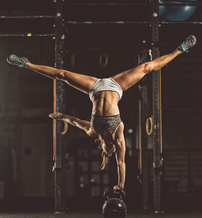 Demi Bagby holding onto a kettlebell while upside down.