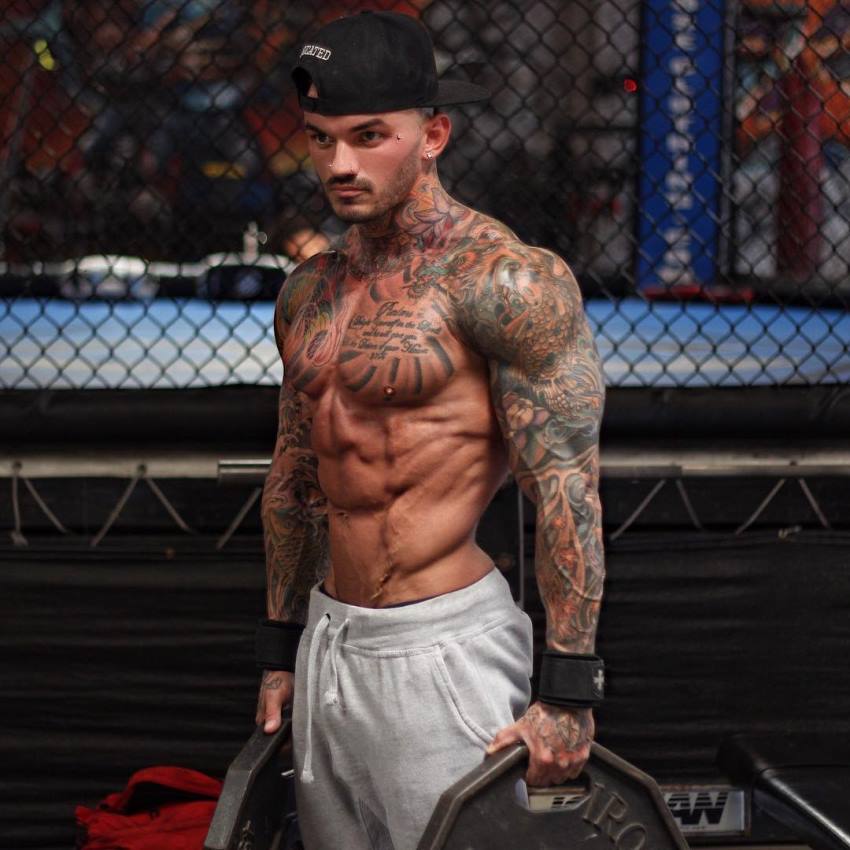 Devin Physique holding weight plates, being shirtless