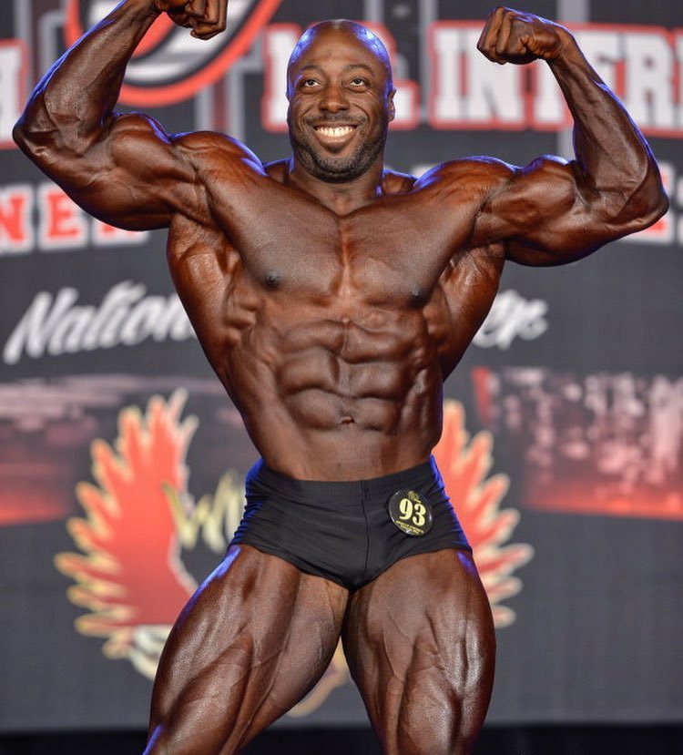 George Peterson showing his front double biceps pose on the bodybuilding stage