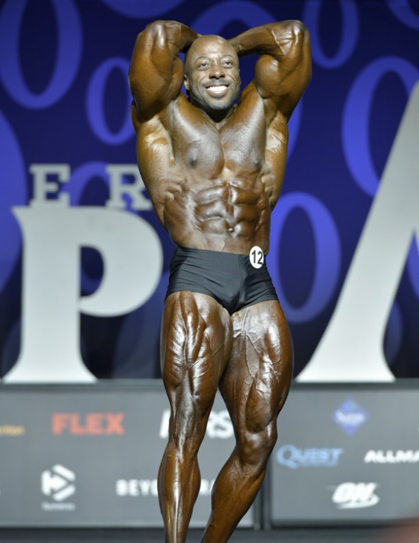 George Peterson flexing his abs and legs at the Mr. Olympia stage