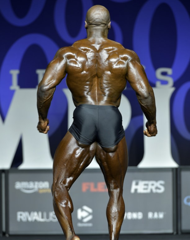 George Peterson flexing his lats, glutes, and hamstrings on the Mr. Olympia Classic Physique bodybuilding stage
