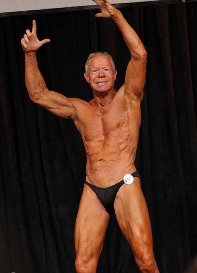 Jim Arrington performing a posing routine on a bodybuilding stage.