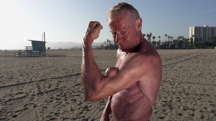 Jim Arrington shirtless on the beach, showing off his remarkable biceps peak