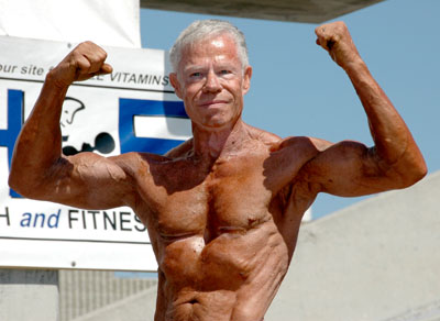 Jim Arrington posing shirtless outdoors, doing a front double biceps flex