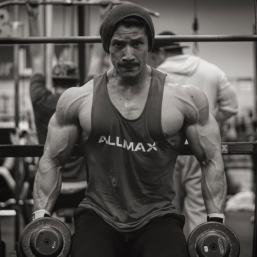 John Nguyen holding dumbbells in the gym.