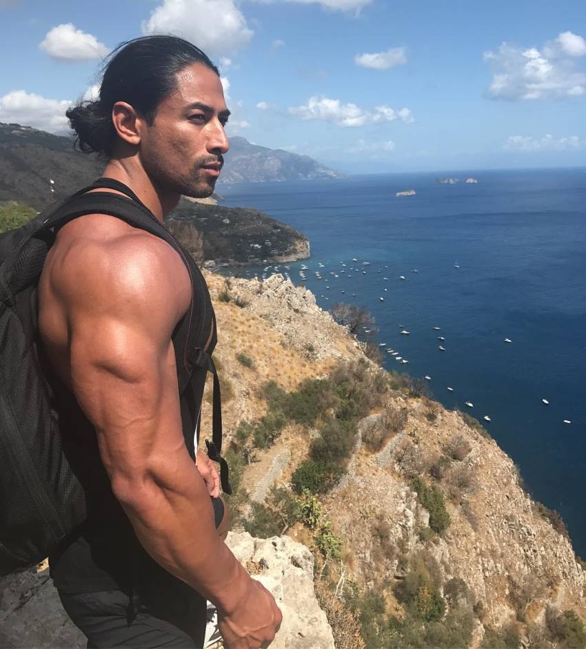 Justin Gonzales standing on the edge of a cliff overlooking a sea