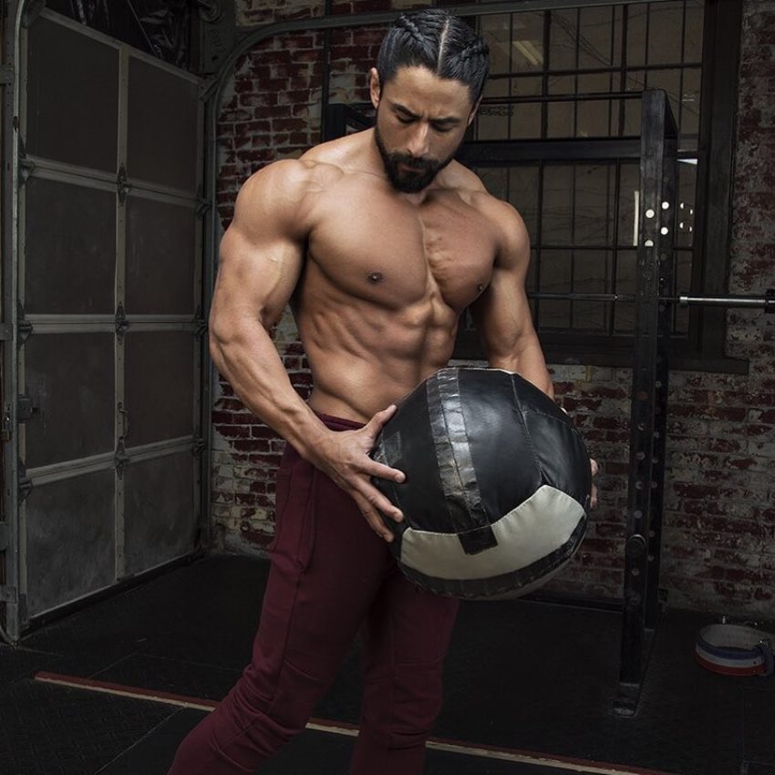 Justin Gonzales holding a ball and showcasting his ripped physique