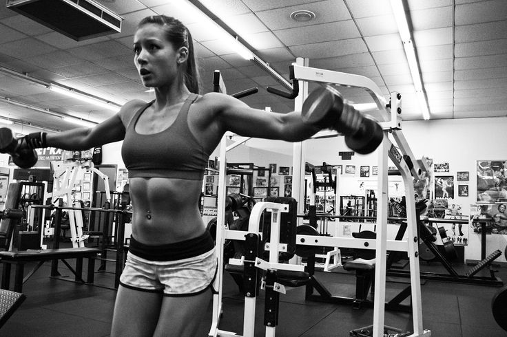 Kimberly Marie doing side lateral raises in the gym.