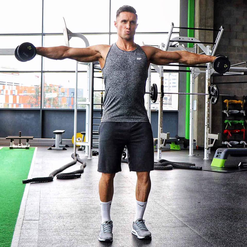 Kirk Miller performing dumbbell lateral raises in the gym.