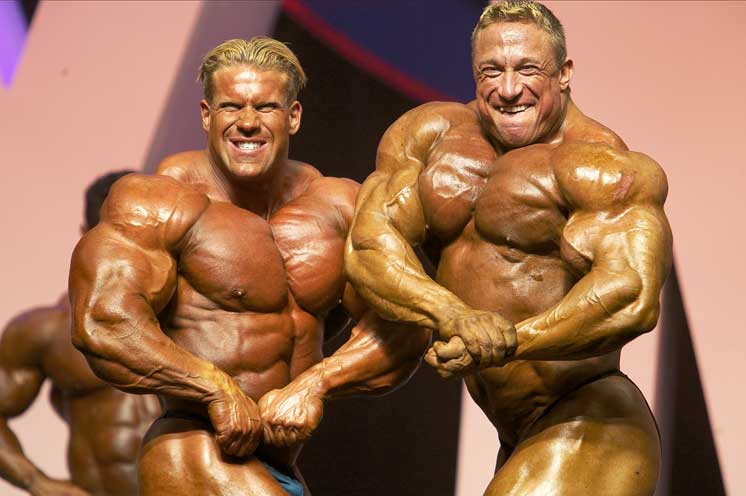 Markus Ruhl doing a side chest pose on the stage standing Next to Jay Cutler