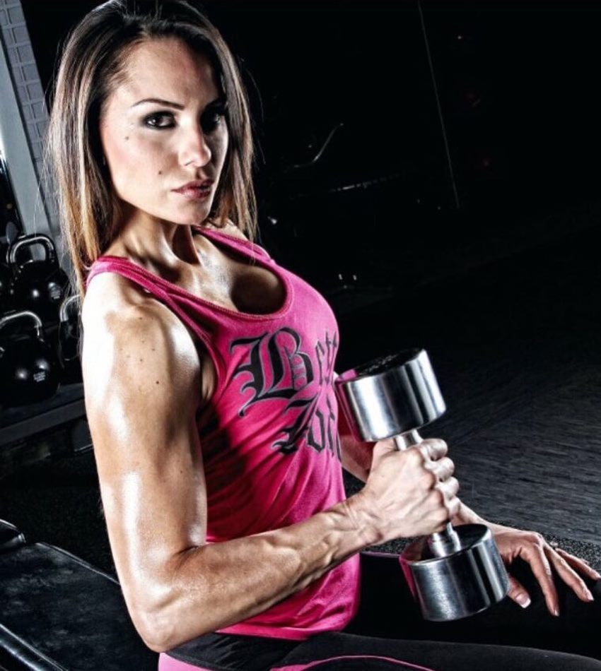 Nathalia Melo with a dumbbell in her hand looking directly at the camera