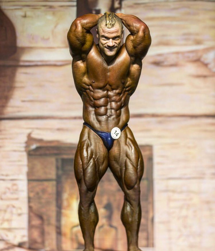 Nicolas Vullioud flexing his abs and legs on the bodybuilding stage, showing off his impressive conditioning