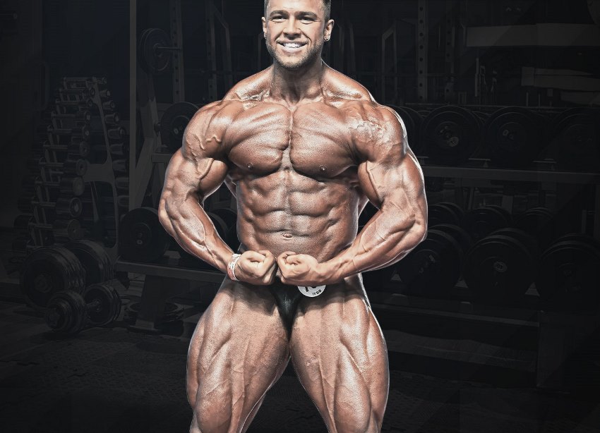 Regan Grimes performing a most muscular pose, looking ripped and huge