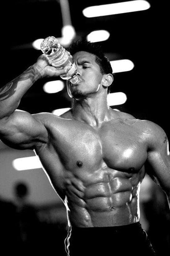 Stan McQuay drinking out of a water bottle showing off his abs.