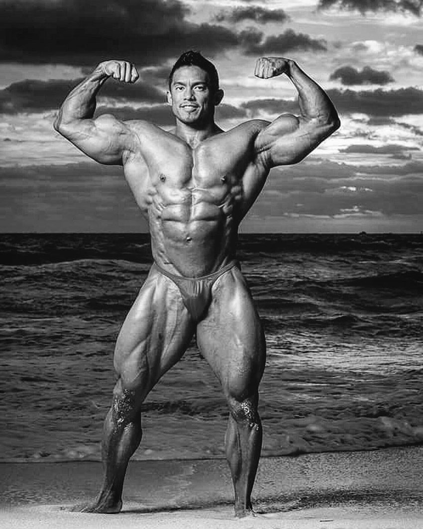 Stan McQuay flexing his arms on the beach.