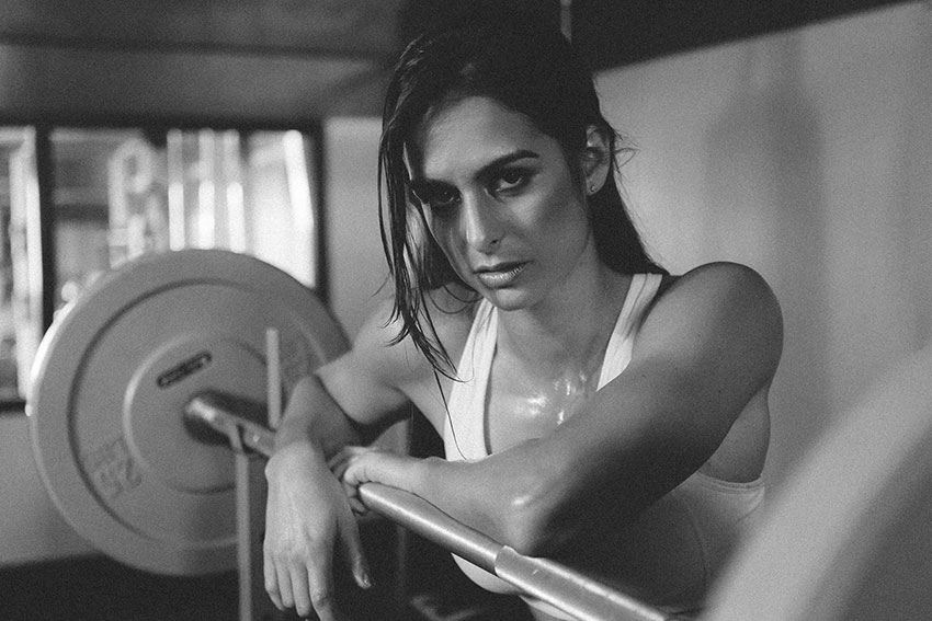 Stephanie Sequeira leaning on a barbell in a photo shoot.