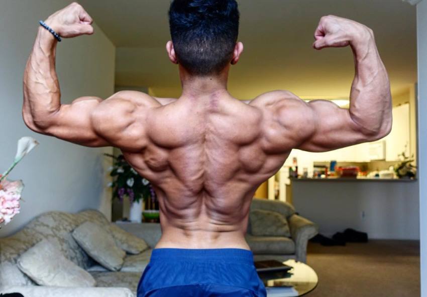 Steven Cao doing a back double biceps pose in living room, looking ripped