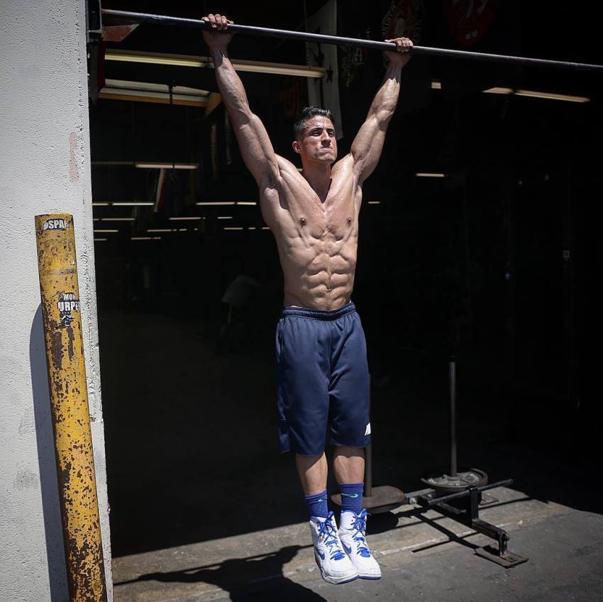 Tomas Echavarria doing hanging leg raises looking fit