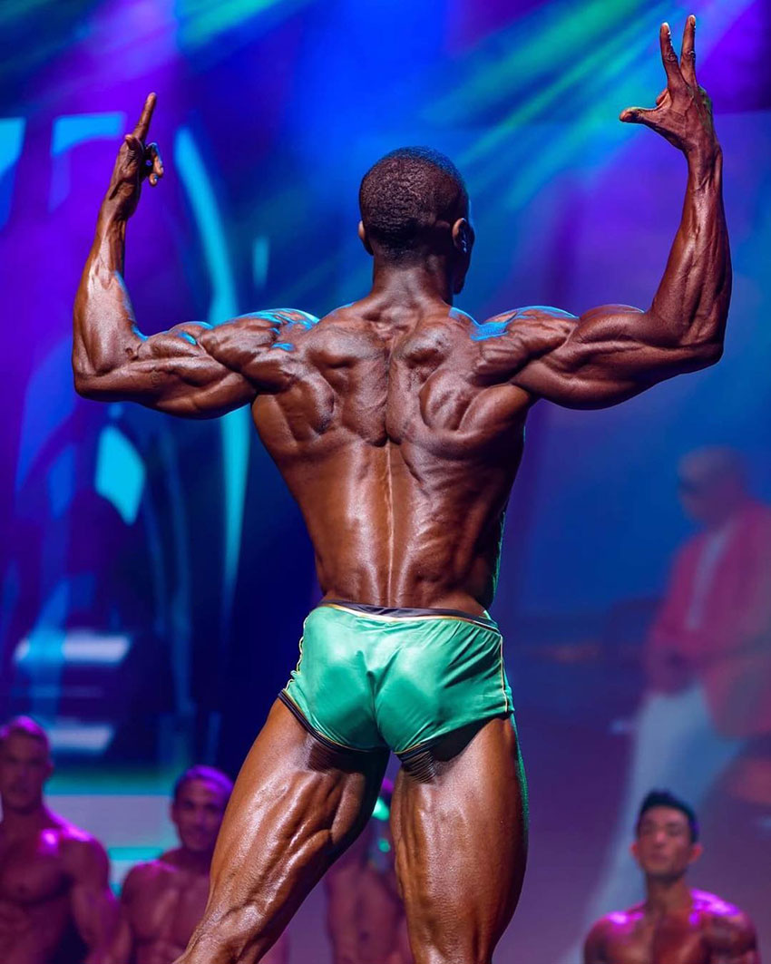 Williams Falade flexing his biceps showing off his back muscles.