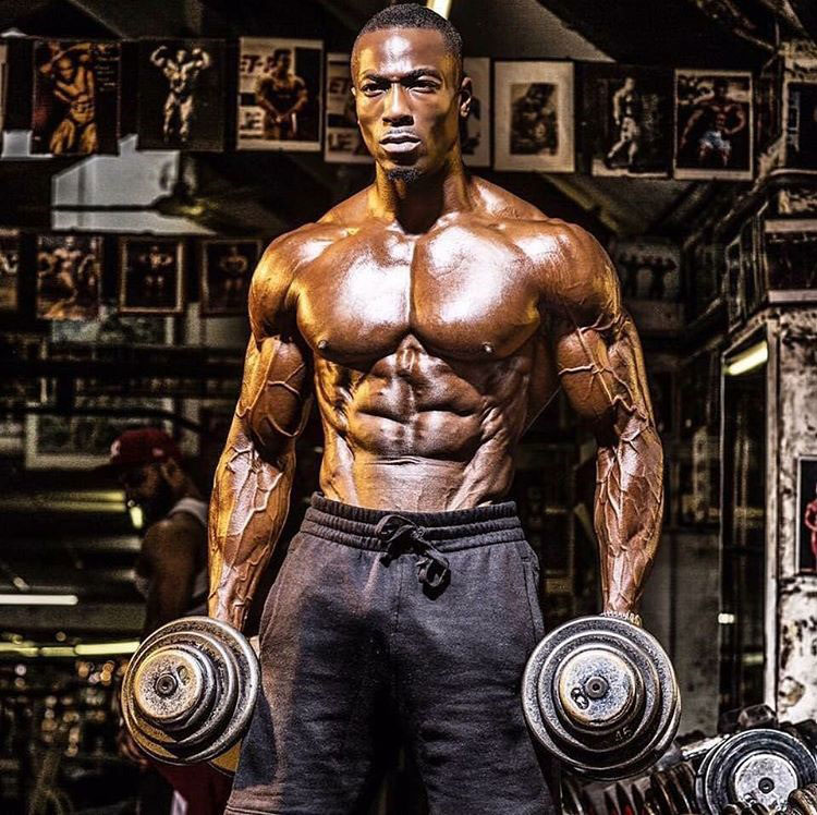 Williams Falade holding dumbbells in the gym.