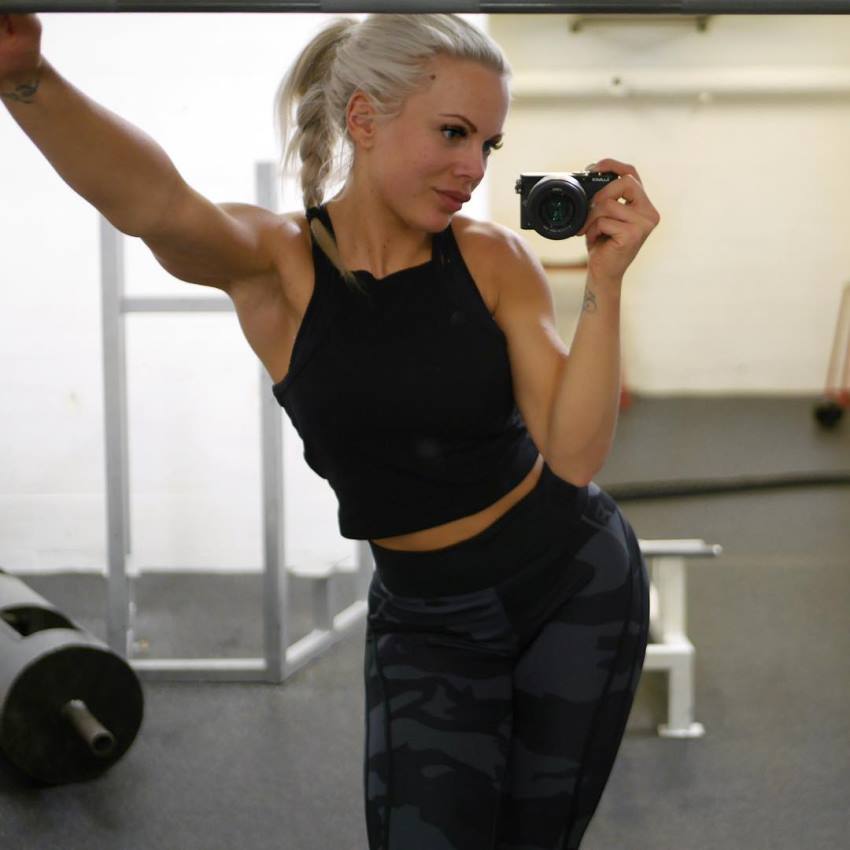 Anna Stålnacke taking a photo of herself by the weights, looking aesthetic and toned