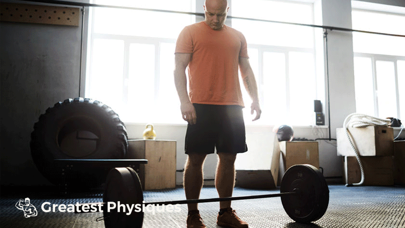 Man in orange tshirt preparing for a heavy deadlift in the gym