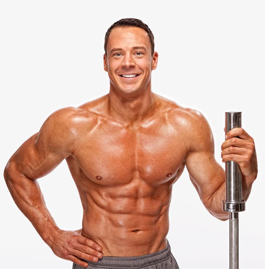 Jeremy Scott smiling at the camera while holding a barbell.