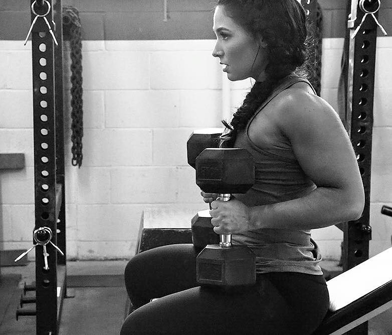 Karina Baymiller holding dumbbells in a photo shoot.