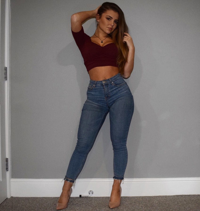 Kate Taylor posing in blue jeans and heels looking fit and lean