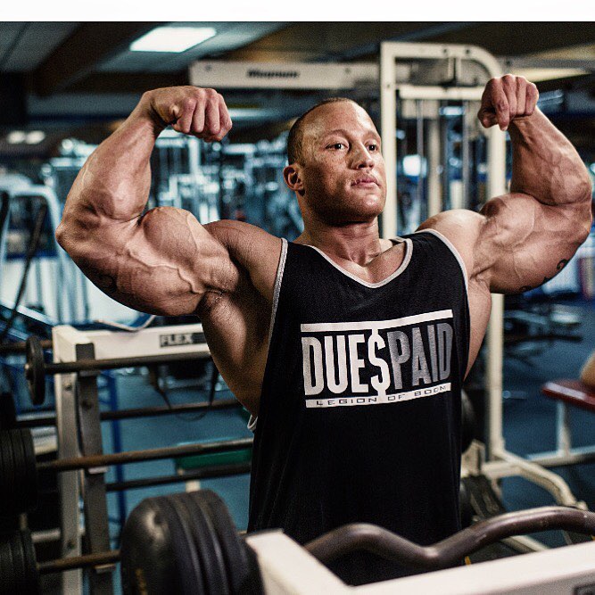 Kevin Jordan flexing his biceps in the mirror in a gym