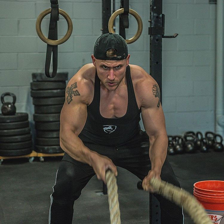 Matty Fusaro exercising in the gym with battle ropes.