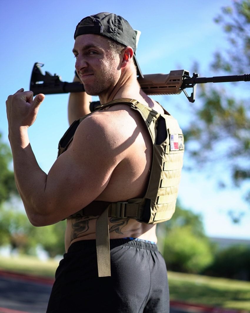 Nick Bare holding a rifle in his arms, looking strong and muscular