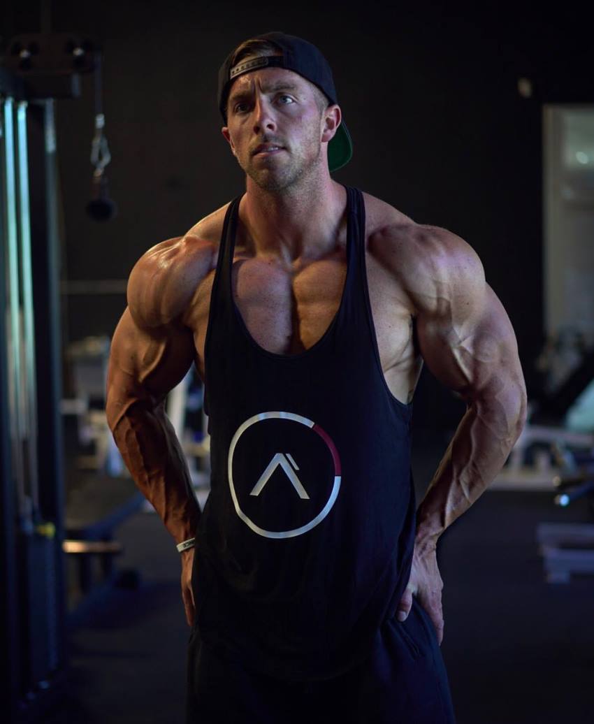 Nick Bare flexing his muscles in a black tank top, looking ripped and muscular