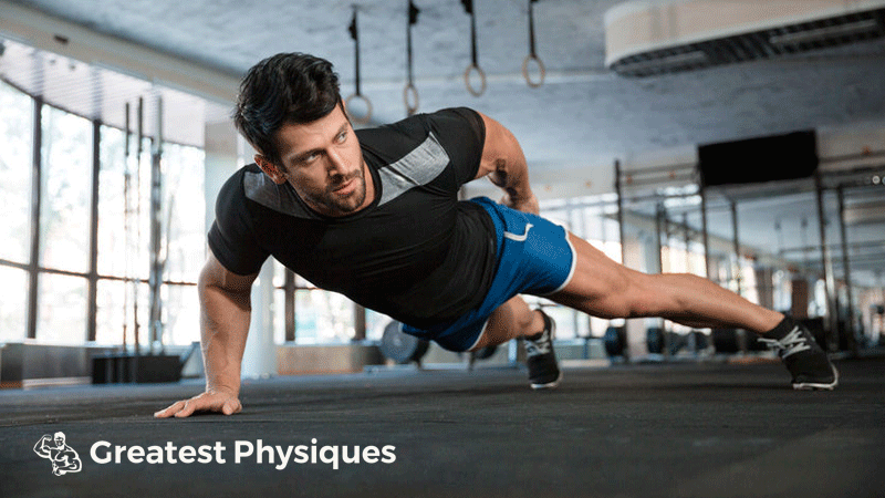 Dark-haired athlete performing one-handed press-ups in the gym