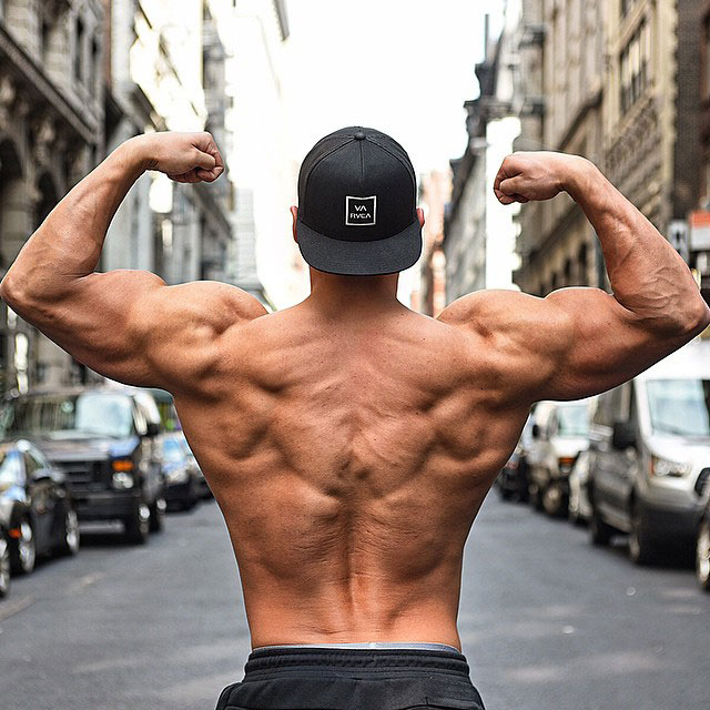 Ryan Hughes showing off his back muscles while flexing his arms.