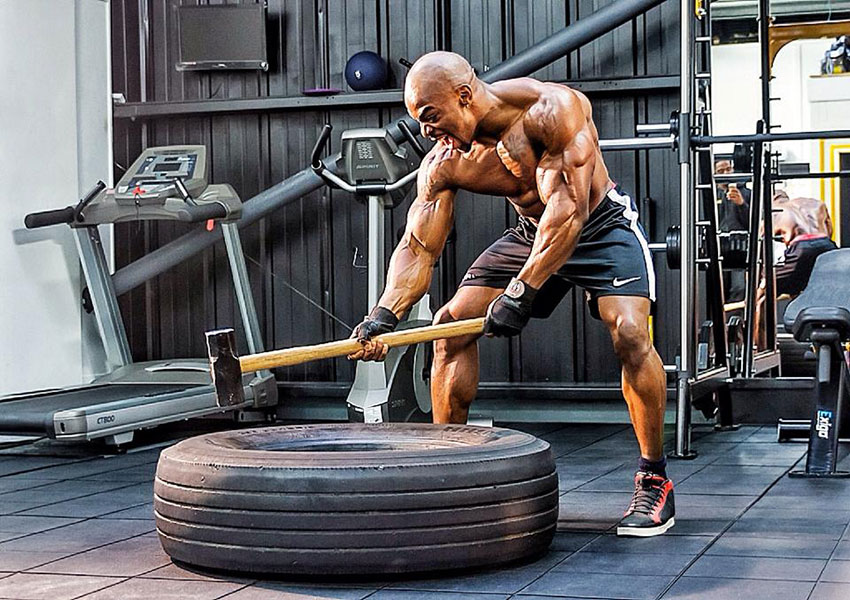 Tyrone Ogedegbe exercising with a sledgehammer in the gym.